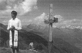 Foto: Kaplan Stefan Müller weiht das mit Alpenblumen geschmückte Gipfelkreuz