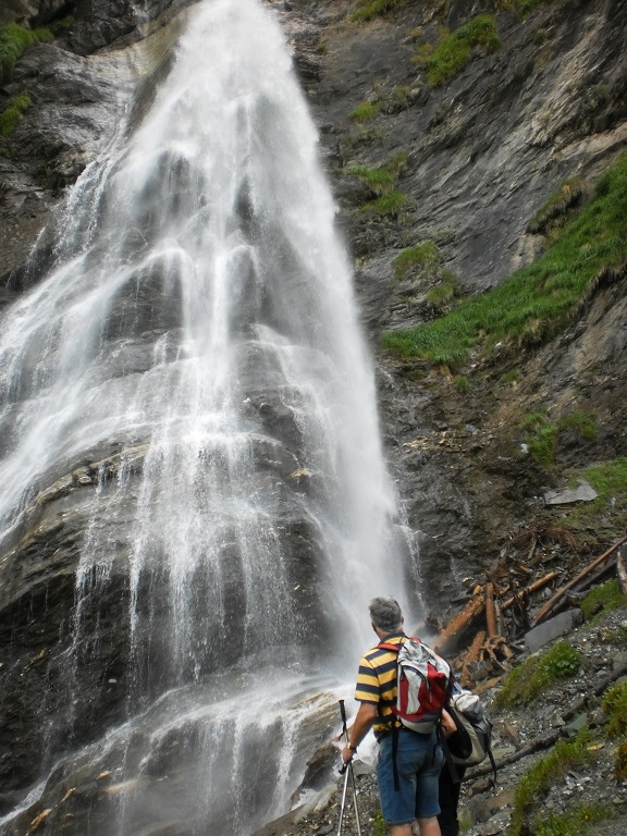 Zwei Wanderer vor einem hohen Wasserfall