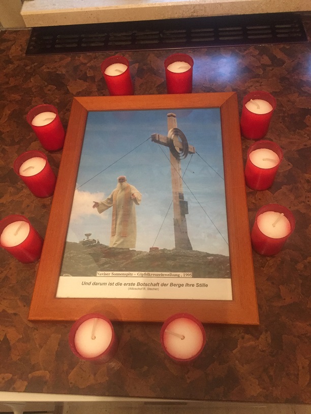 Kerzen um Gedenkbild, Aufschriften: Naviser Sonnenspitz - Gipfelkreuzeinweihung, 1995; Und darum ist die erste Botschaft der Berge ihre Stille (Altbischof R. Stecher)