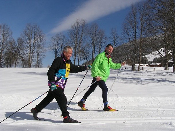 Nebeneinander Schi-laufend genießen zwei Ski-Langläufer die gut gespurte Loipe und den herrlichen Wintertag.